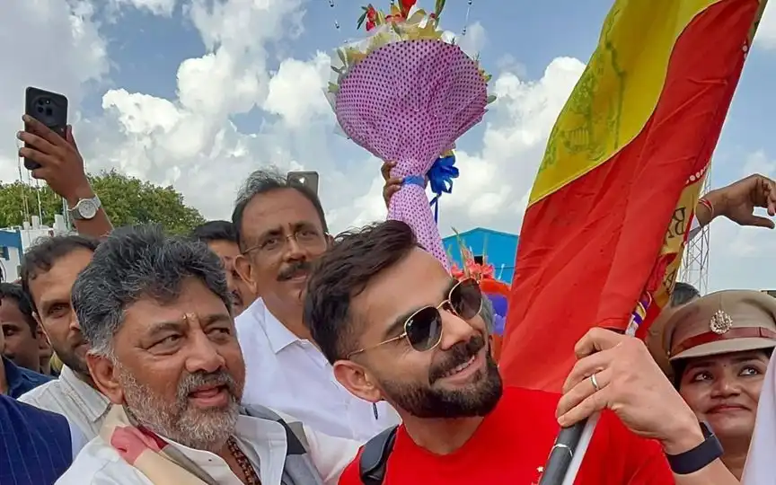 कर्नाटक का झंडा लेकर चलते विराट कोहली (Source: @mufaddal_vohra/x.com)